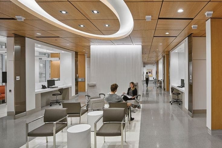 Healthcare waiting corridor with patient seating, curved ceiling bulkheads and a reception counter